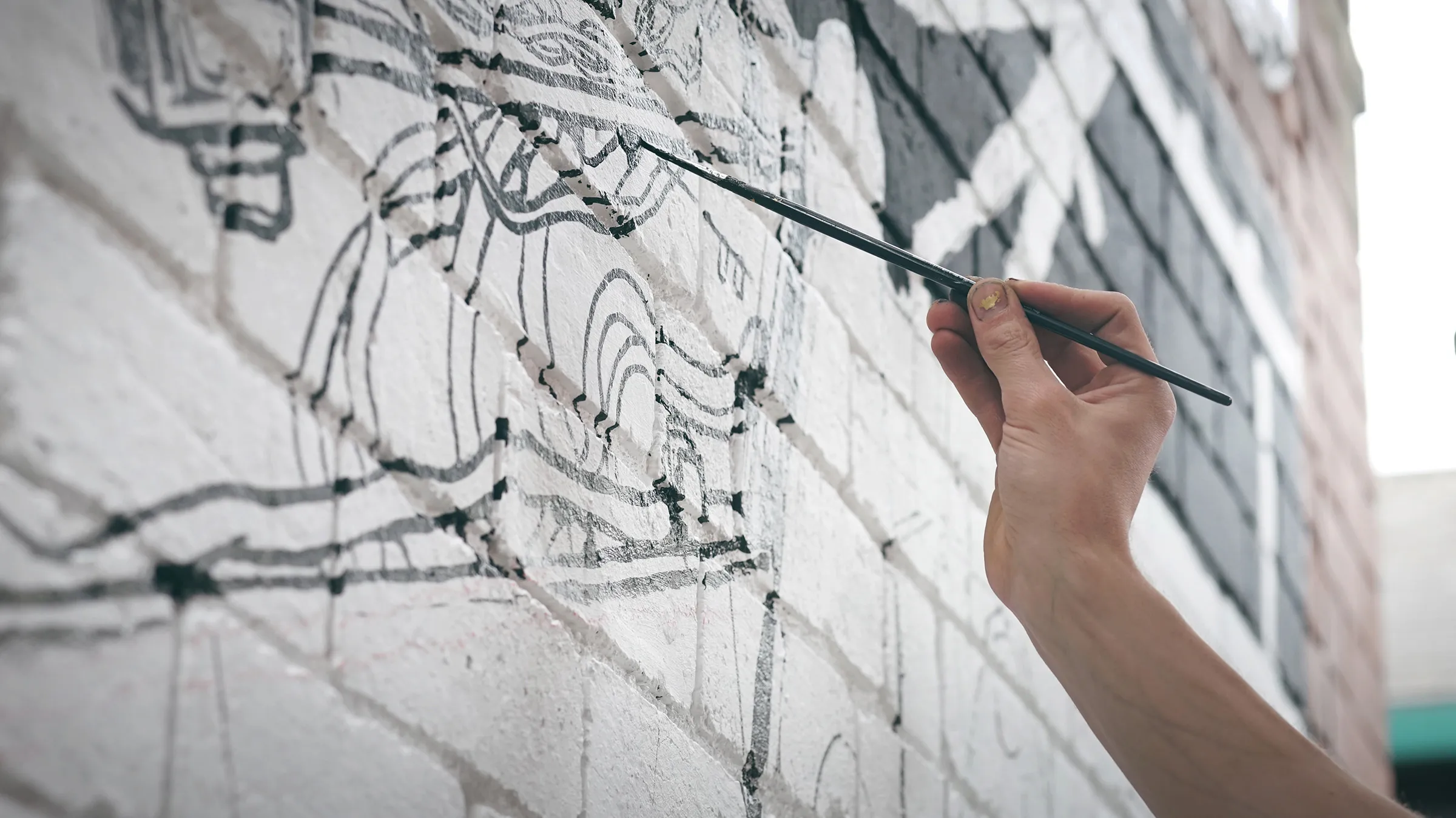 Painting the line work onto a white brick wall with a fine brush.