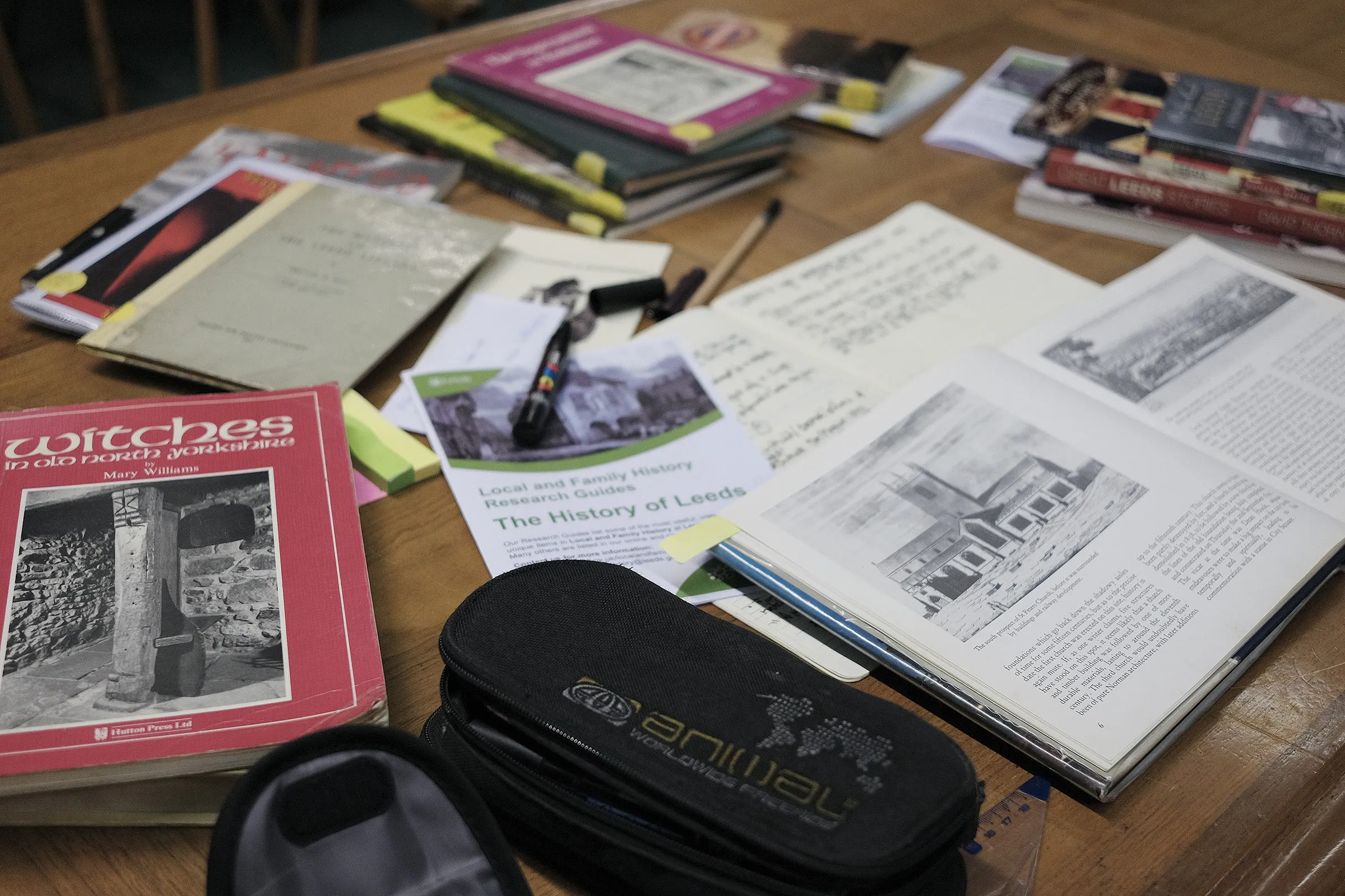 Research spread across a table: local history books, printouts and notebooks.