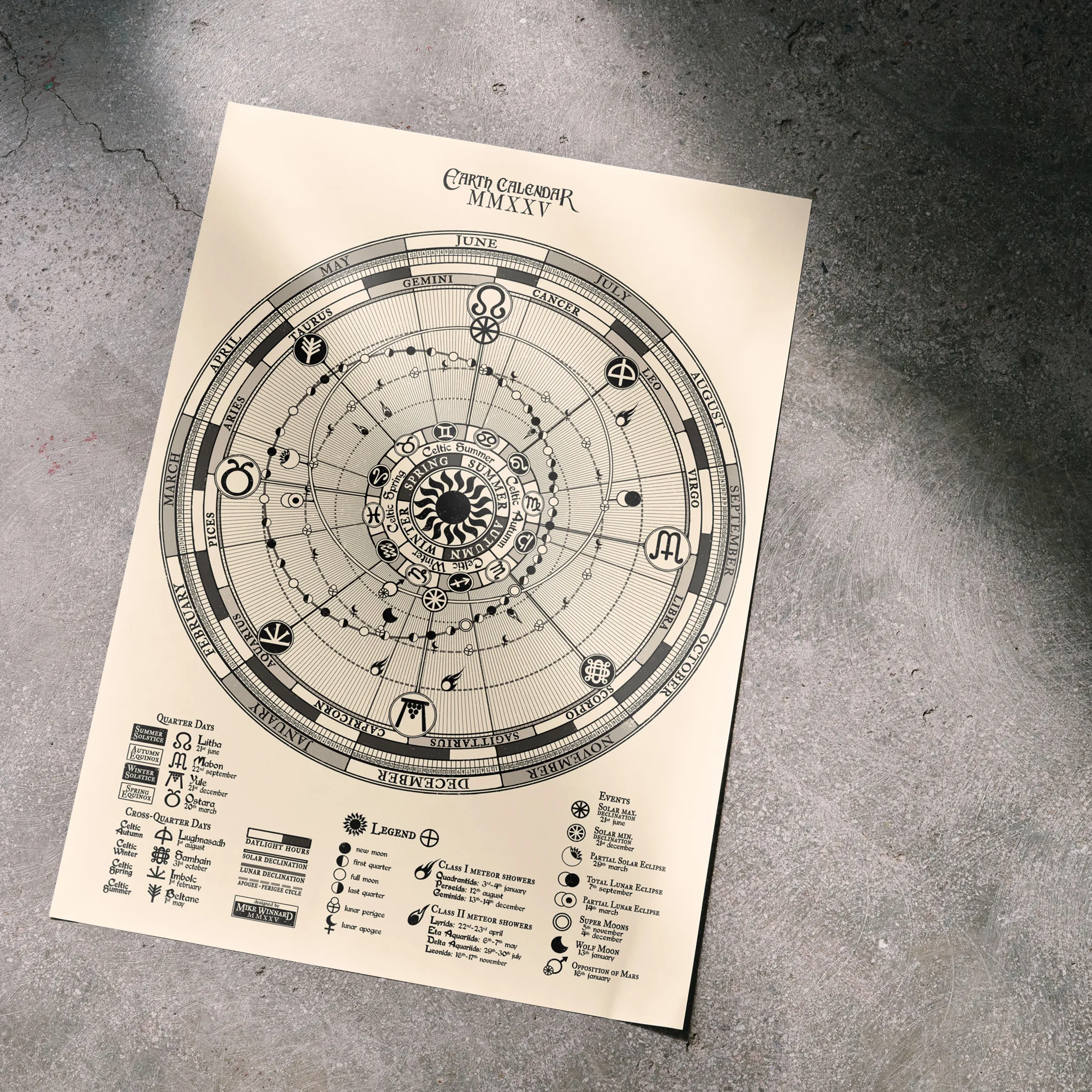 The black-on-cream calendar lying on a concrete floor in soft window light.