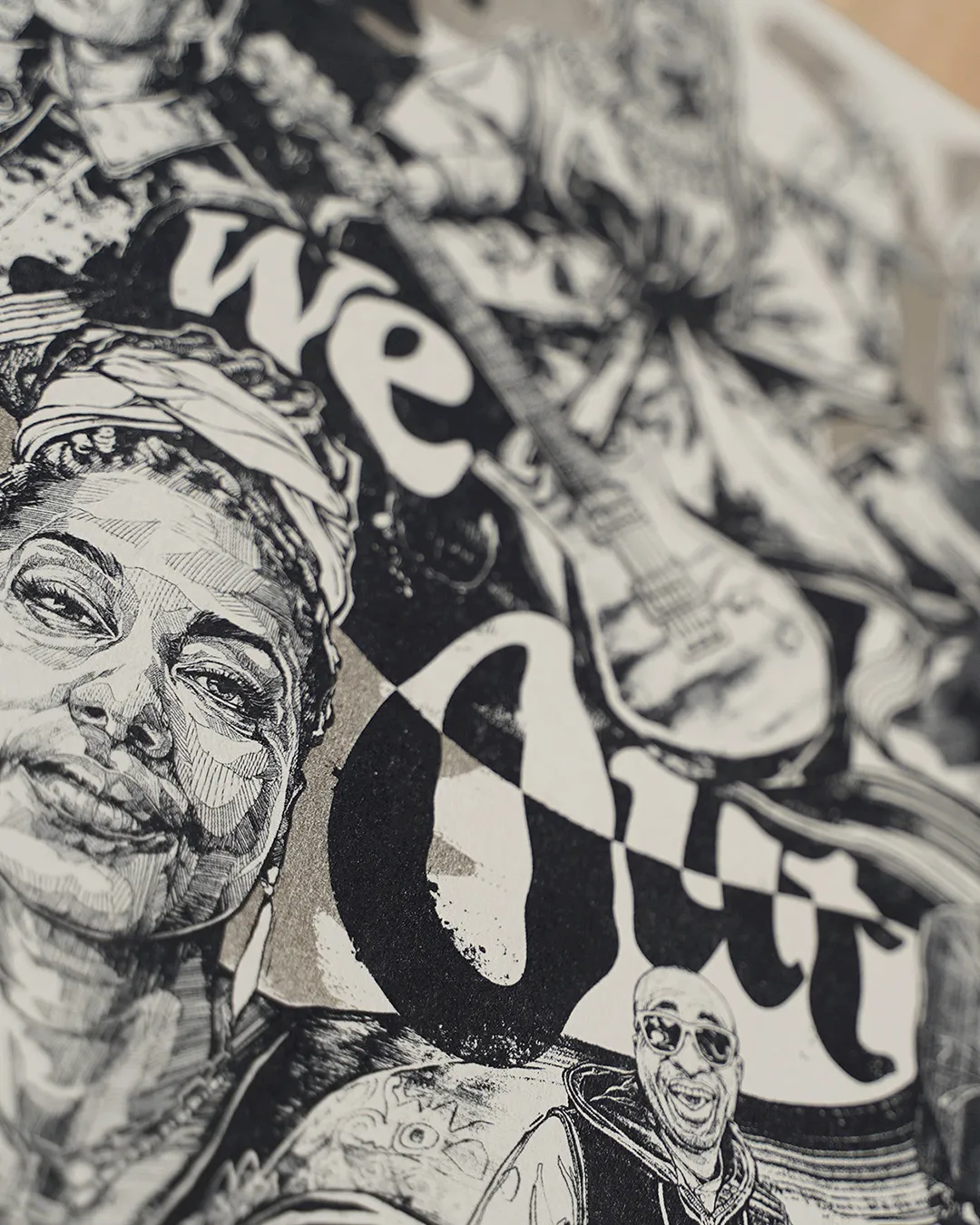Close-up of a black and white print: a drawn portrait beside the bold letters of "We Out".